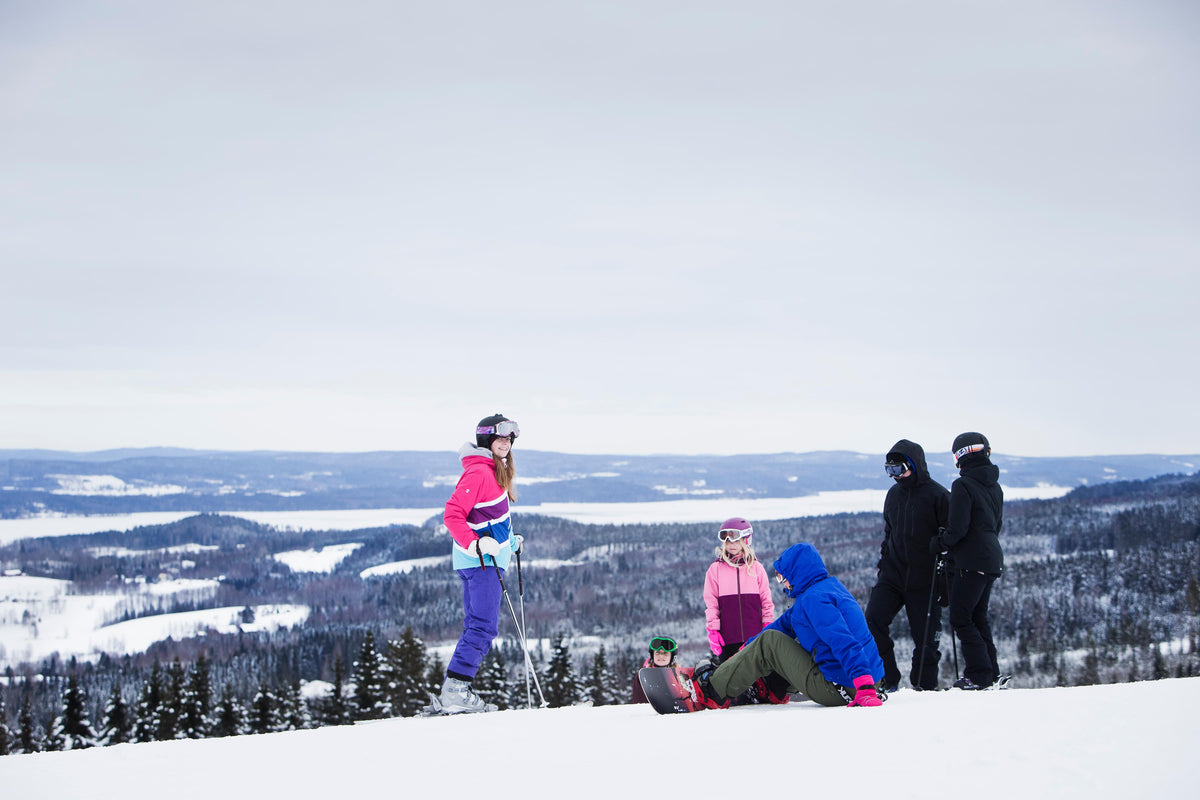 Skidlektion för barn: flera barn i skidkläder på snö vid fjällutsikt