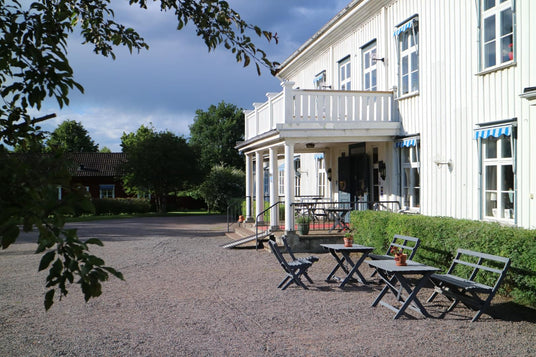 Sommarpaket boende: vit byggnad med uteplatsstolar och bord