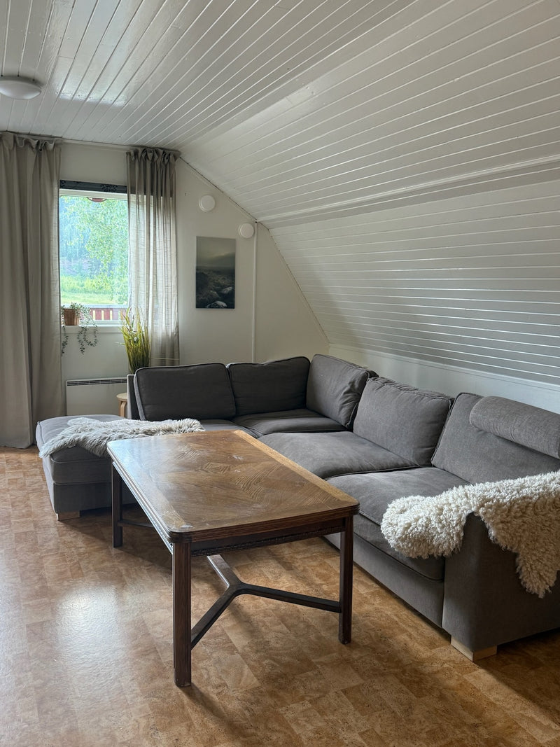 Gemensamt vardagsrum med hörnsoffa under snedtak