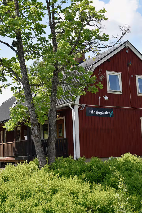 Röd träbyggnad med fönster och Hånsjögården-skylt