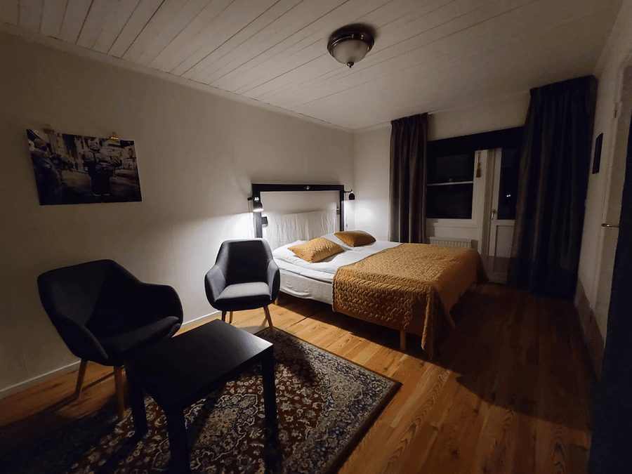 Sovrum med dubbelsäng, sängbordslampa och två fåtöljer samt heltäckningsmatta